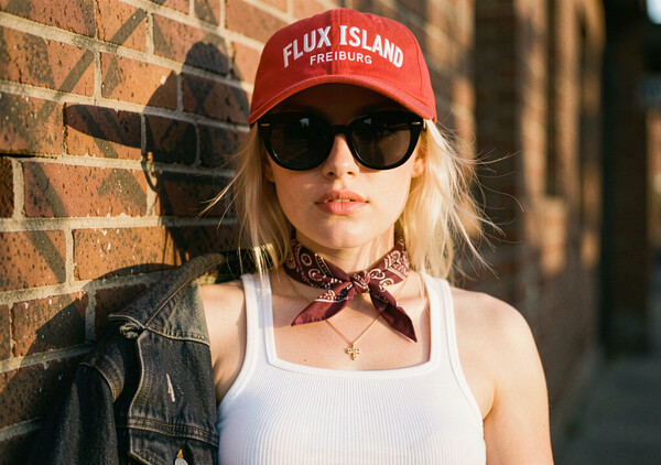 Flux 2 Klein example: blonde woman in red cap and bandana against a sunlit brick wall